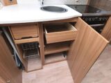 The stainless steel sink and kitchen cupboards