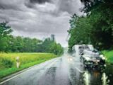 A car towing a caravan driving down a road in the rain