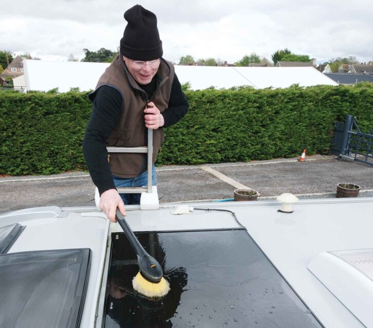 A man cleaning a solar panel on the roof