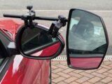 A close up of a towing mirror in place on a red car