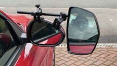 A close up of a towing mirror in place on a red car