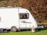 A caravan with solar panels resting against it