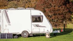 A caravan with solar panels resting against it
