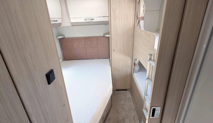 The fixed double bed, the bunk beds, and overhead lockers at the rear of the van
