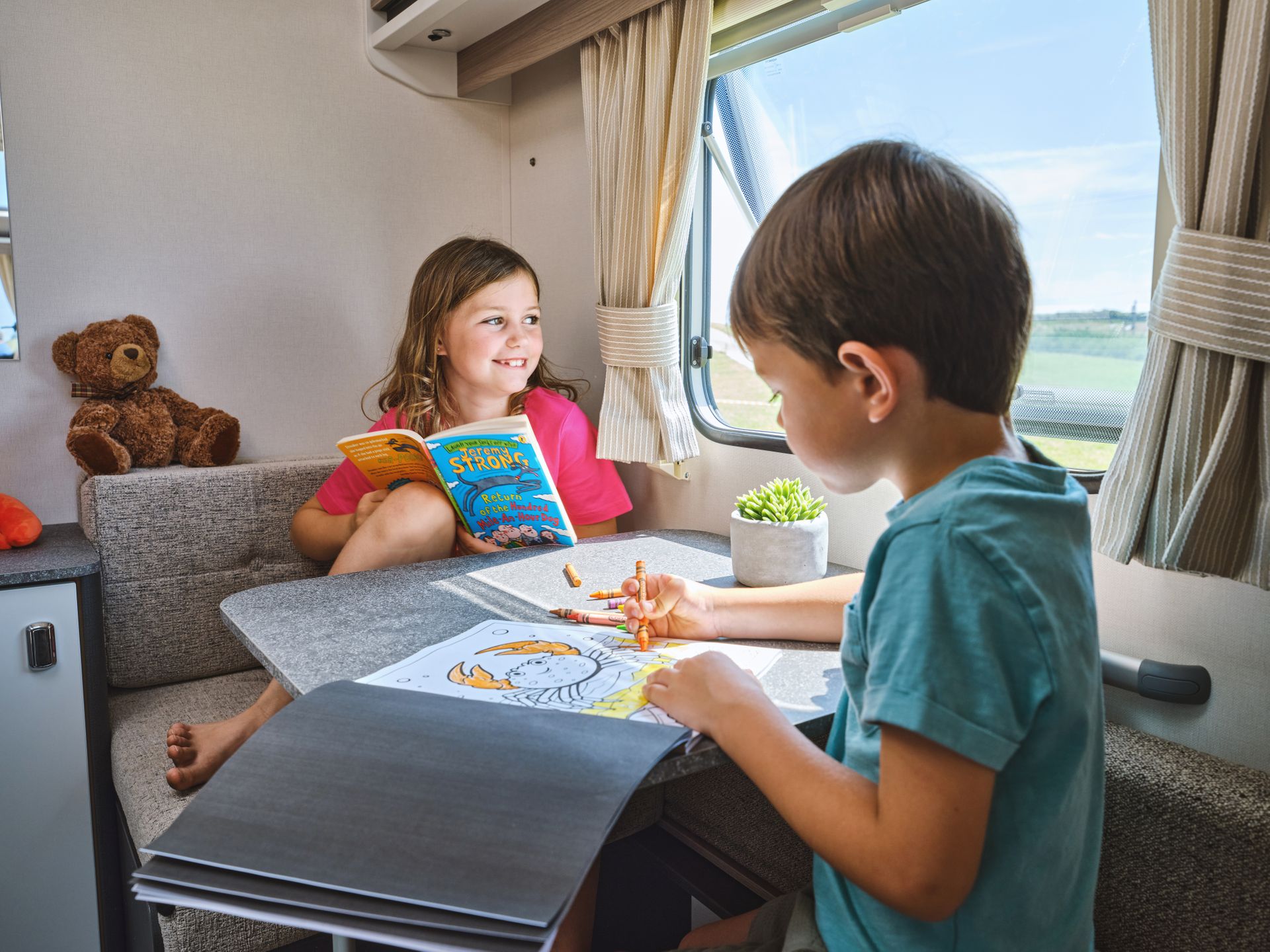 Two children in the dinette of a Swift Sprite caravan