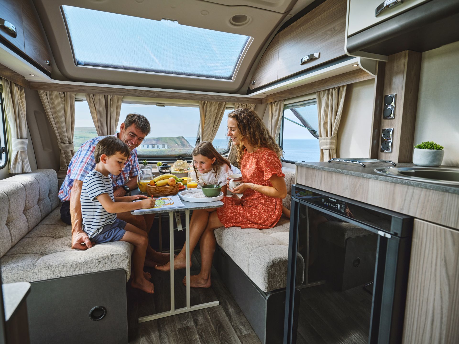 Family sitting in the front lounge of a Swift Sprite caravan