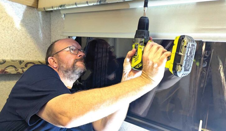 Nigel with a drill in hand in the middle of repairing the blinds