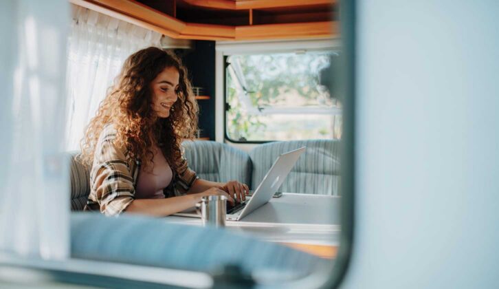 A woman on a laptop in a caravan