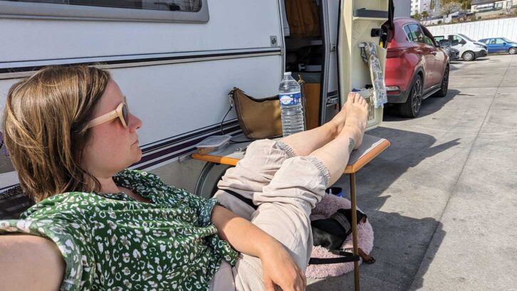 Lottie sitting back with her feet up as she waits at the 'dead car depot', while Arty lays under a table