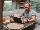 A man on a laptop in a caravan