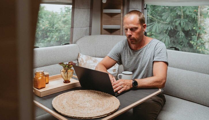 A man on a laptop in a caravan