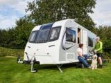 Sarah with her dog talking to a cyclist on-site by a caravan