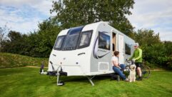 Sarah with her dog talking to a cyclist on-site by a caravan