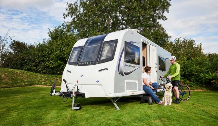 Sarah with her dog talking to a cyclist on-site by a caravan