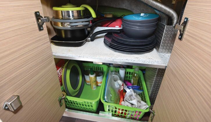 A cupboard with storage trays and folding pans