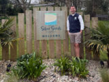 A man standing by the Silver Sands Holiday Park sign