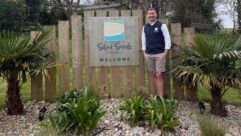 A man standing by the Silver Sands Holiday Park sign