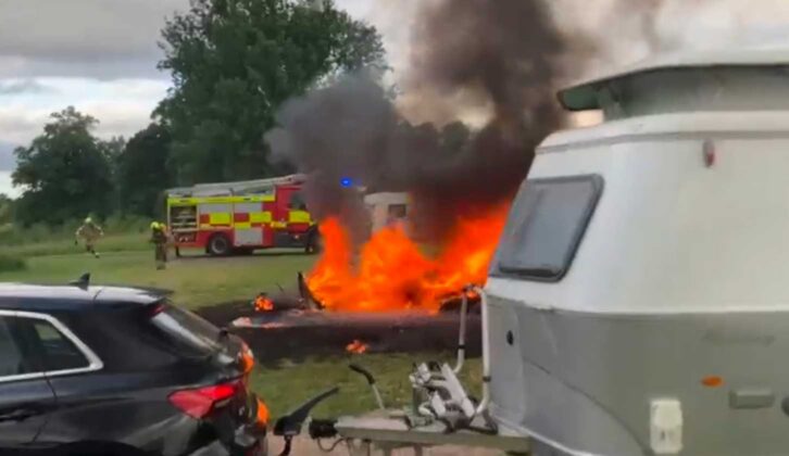 The caravan burning in the background while another caravan is hitched up to a tow car in the foreground