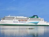 An Irish Ferries ferry at sea while a smaller boat is rowed past in the the foreground