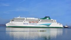 An Irish Ferries ferry at sea while a smaller boat is rowed past in the the foreground