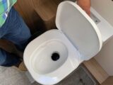 A person flushing a caravan toilet