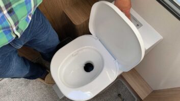 A person flushing a caravan toilet