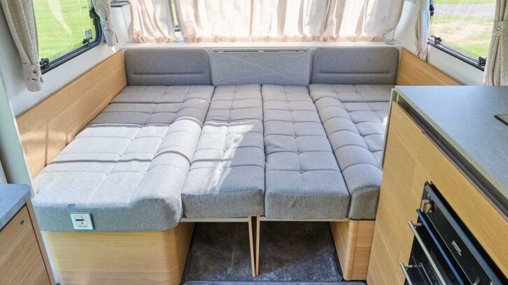 A bed made up in the lounge of a caravan