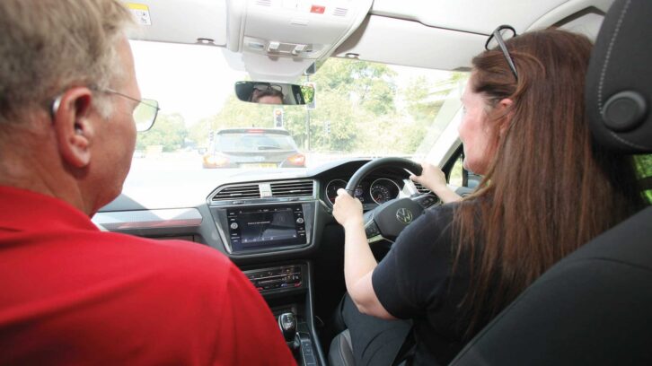 A person driving a car with encouragement coming from the person in the passenger seat