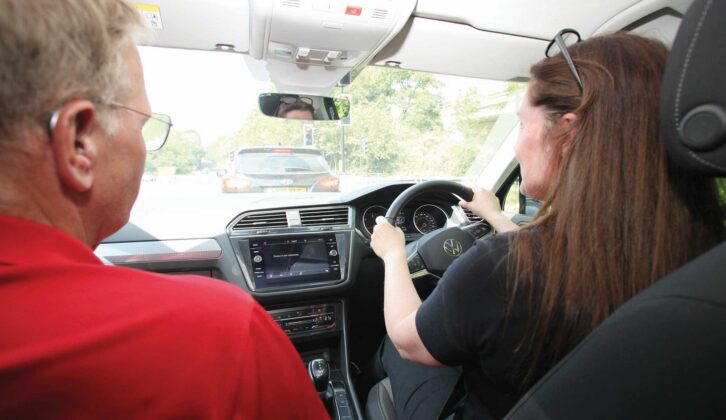 A person driving a car with encouragement coming from the person in the passenger seat