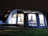 A caravan pitched up with an awning at night