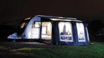 A caravan pitched up with an awning at night