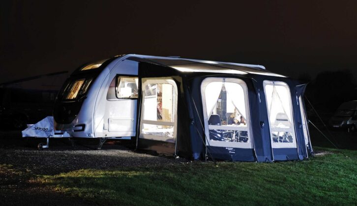 A caravan pitched up with an awning at night