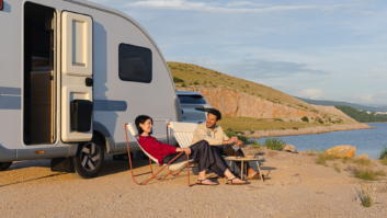 Exterior shot of Adria's Action caravan with a couple sitting outside